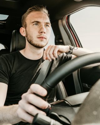 мужчина сидит за рулем автомобиля, улыбается